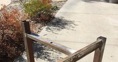 a wooden fence sitting on the side of a road next to a bush and bushes