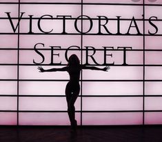 a woman standing in front of a wall with the words victoria's secret on it