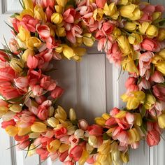 a wreath made out of tulips is hanging on the front door with flowers in it