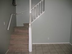 an empty room with stairs and tiled floor