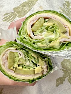 two wraps filled with lettuce and meat on top of a white table cloth