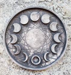 a metal plate with moon phases in the center on a stone surface, as seen from above