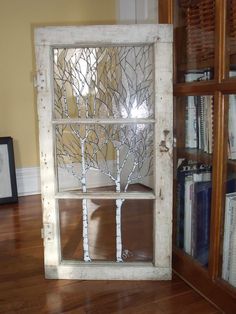 an old window has been decorated with branches and leaves on the front, and is being displayed