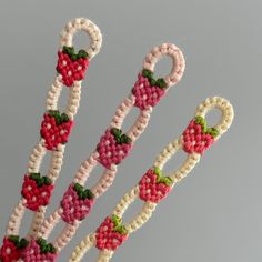 three knitted candy canes are in the shape of strawberries