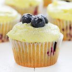 cupcakes with frosting and blueberries on top sitting on a white table