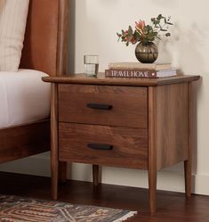 a nightstand with two drawers and a book on top