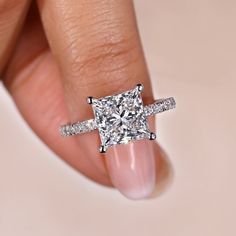 a woman's hand holding a diamond ring