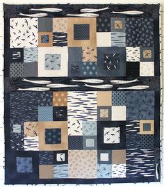 a black and white patchwork quilt hanging on a wall