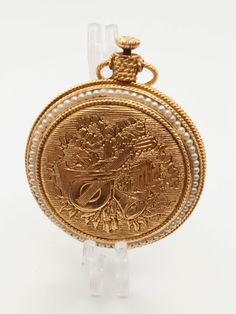 an old gold pocket watch with pearls on it