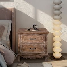 a bedroom scene with focus on the nightstand and bed side table that has a lamp next to it