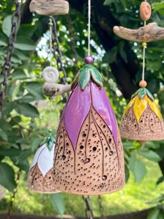 three decorative hanging lights in the shape of flowers and leaves on a tree branch with green foliage behind them