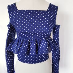 Unique ,pretty polka dot top has a button fastening at back with long narrow sleeves that flare out at cuffs. The sleeves are set with bare shoulders. It is close fitting, with peplum skirt that sits just under the bust and is a short cropped style. This top is XS , fitting someone of UK size 6 /8. Bust of 30/31  inches (80 cm ), waist of 24/26 inches,61 cm ) Polka Dot Long Sleeve Party Tops, Polka Dot Long Sleeve Tops For Party, Fitted Long Sleeve Peplum Top For Party, Long Sleeve Polka Dot Blouse For Summer, Fitted Long Sleeve Chic Peplum Top, Chic Fitted Long Sleeve Peplum Top, Fitted Long Sleeve Polka Dot Blouse, Spring Long Sleeve Peplum Top For Party, Fitted Polka Dot Top For Spring