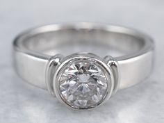 a white gold engagement ring with a round cut diamond in the center on a marble surface