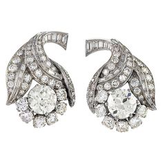 These curvaceous French Late Art Deco platinum flower earrings, with over fourteen carats of diamonds, possess all the glamour of Hollywood's golden age. Set with baguette-cut diamonds, the curving stem branches into three leaves set with round-cut diamonds. Nestled inside the three leaves is the flower itself, centering on a large brilliant-cut round diamond enclosed by smaller round-cut diamonds. Circa: 1930s Size: 1.5” length, 0.875” width Materials: 38 Baguette-cut diamonds (approximate total weight 3.00 carats); 40 Round-cut diamonds (approximate total weight 6.20 carats); 2 Old European-cut diamonds (approximate weight 2.35 carats and 2.50 carats); Platinum Diamond Flower Earrings, Late Art, Diamond Chandelier Earrings, Diamond Jewelry Earrings, Sapphire And Diamond Earrings, Diamond Cluster Earrings, Platinum Earrings, Earrings For Sale, Vintage Fine Jewelry