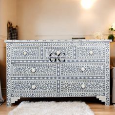 an ornate blue and white dresser in a living room with sheepskin rug on the floor