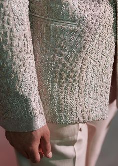 a close up of a person's hand wearing a white suit and holding onto the back of his jacket