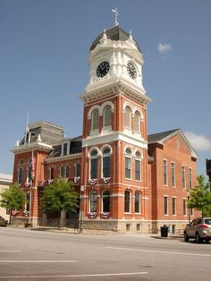 an old brick building with a clock tower on the top and american flags hanging from it's sides