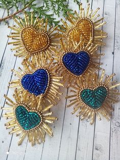 three sunbursts with blue, green and gold beads sitting on top of a wooden