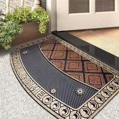 a black and gold door mat on the ground next to a potted green plant