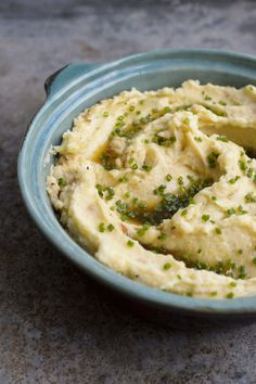 a blue bowl filled with mashed potatoes on top of a gray countertop next to a knife