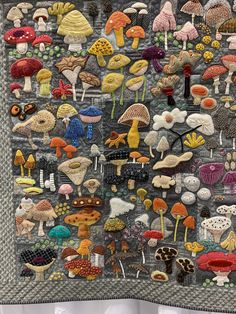 a quilted wall hanging with many different types of mushrooms