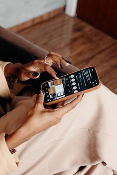 a woman holding a smart phone in her hand and typing on the screen with both hands