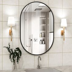 a bathroom with a sink, mirror and lights on the wall next to a potted plant