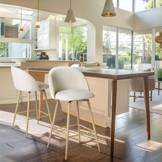 two white chairs sitting at a wooden table in a room with high ceilings and floor to ceiling windows