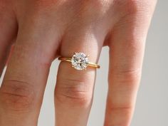 a woman's hand with a diamond ring on top of her finger, showing the center stone