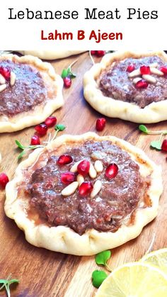 three small pizzas on top of a wooden cutting board with pomegranate