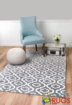 a blue chair sitting on top of a wooden floor next to a white and gray rug