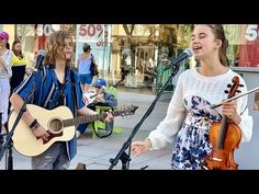 two women singing and playing instruments in front of a microphone