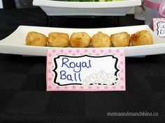 some food is on a white plate and black table cloth with pink polka dot tags