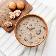 a bowl of mushroom soup next to some mushrooms on a cutting board