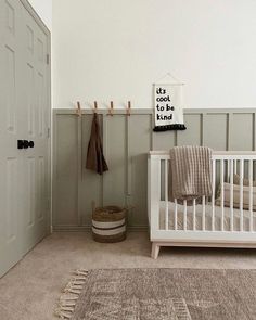 a baby's room with a white crib, rug and coat rack on the wall