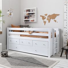 a child's bedroom with white furniture and a map on the wall above it