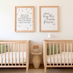 two baby cribs with posters on the wall above them and a lamp next to it