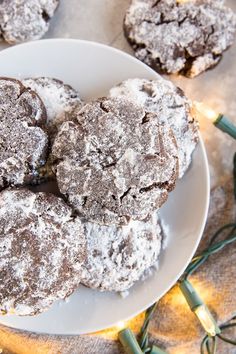 powdered sugar cookies on a white plate with christmas lights in the backround