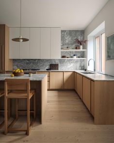 a large kitchen with wooden cabinets and marble counter tops, along with an island in the middle