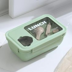 a lunch box sitting on top of a counter with utensils in the container