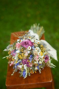 a bouquet of flowers on top of a wooden table in front of a grass field