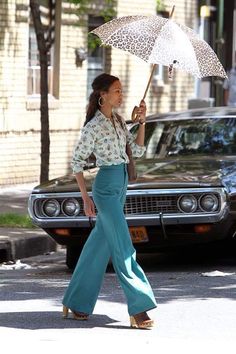 a woman is walking down the street with an umbrella in her hand and leopard print shirt on