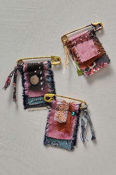 three pieces of fabric hanging from hooks on a white surface with beads and other items