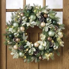 a christmas wreath on a door with pine cones and greenery hanging from the front