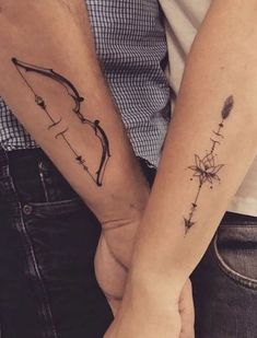 two people holding hands with tattoos on their arms