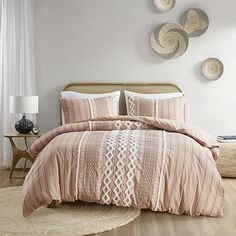 a bed in a bedroom with pink comforter and pillows