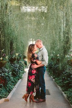 a man and woman kissing in front of some plants