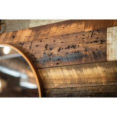 a mirror hanging on the side of a wooden wall next to a light fixture and wood planks