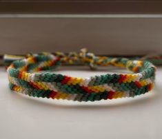 a multicolored bracelet sitting on top of a white table next to a pair of scissors