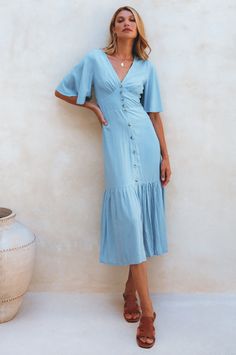 The simple yet charming Donna midi dress screams elegance and femininity. Handcrafted from soft breathable rayon into a button-down silhouette with a smock waist on the back and fitted detailing on the front it cascades into a tiered skirt and is adorned with tortoise buttons and butterfly sleeves. Style Donna with a pair of low-heel slides for the perfect coastal summer look. Content: 100% Rayon Hand wash warm Button-down silhouette Elasticated waist on the back Button-up closure Midi length Un Summer Mid-length Dress With Button Closure, V-neck Midi Dress With Button Closure For Brunch, Flowy Button-up Midi Dress For Daywear, Casual Flowy Maxi Dress With Button Closure, Beach Midi Dress With Buttons Knee-length, Knee-length Midi Dress With Buttons For Beach, Fitted Rayon Midi Dress For Brunch, Beach Midi Dress With Button Closure, Elegant Beach Midi Dress With Buttons